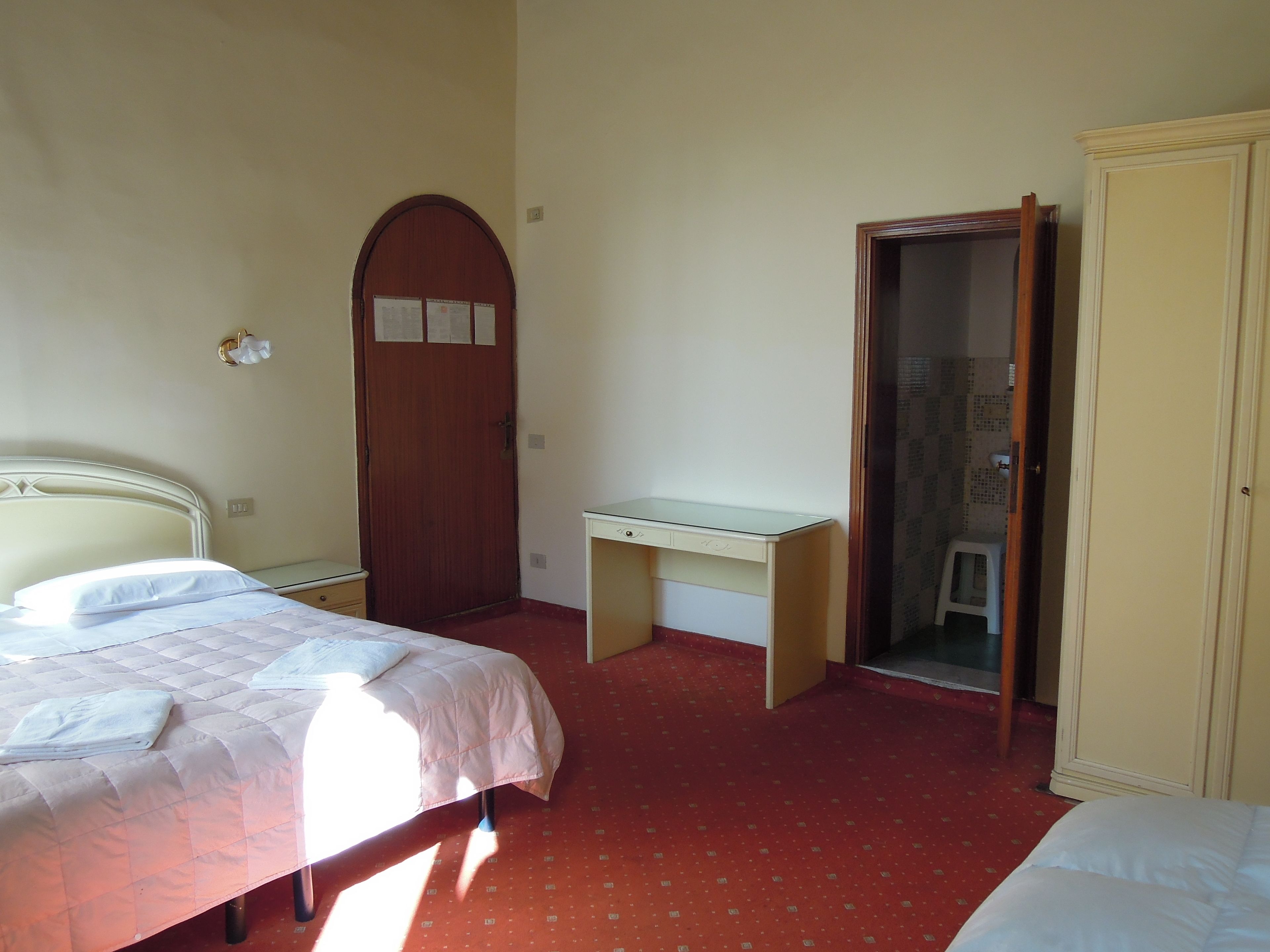 A bedroom with two beds, a desk, and a wardrobe.