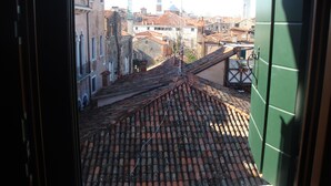 Une vue depuis une fenêtre donnant sur un paysage urbain, avec des bâtiments traditionnels et un imposant beffroi.