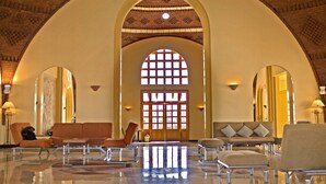 Een lobby met een hoge gewelfde plafond, een groot centraal raam en zithoekjes.