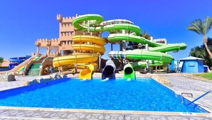 Een waterpark met glijbanen en een kasteelachtige constructie op de achtergrond.