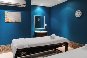 Una habitación con una cama, un lavabo, un espejo y un reloj en la pared.