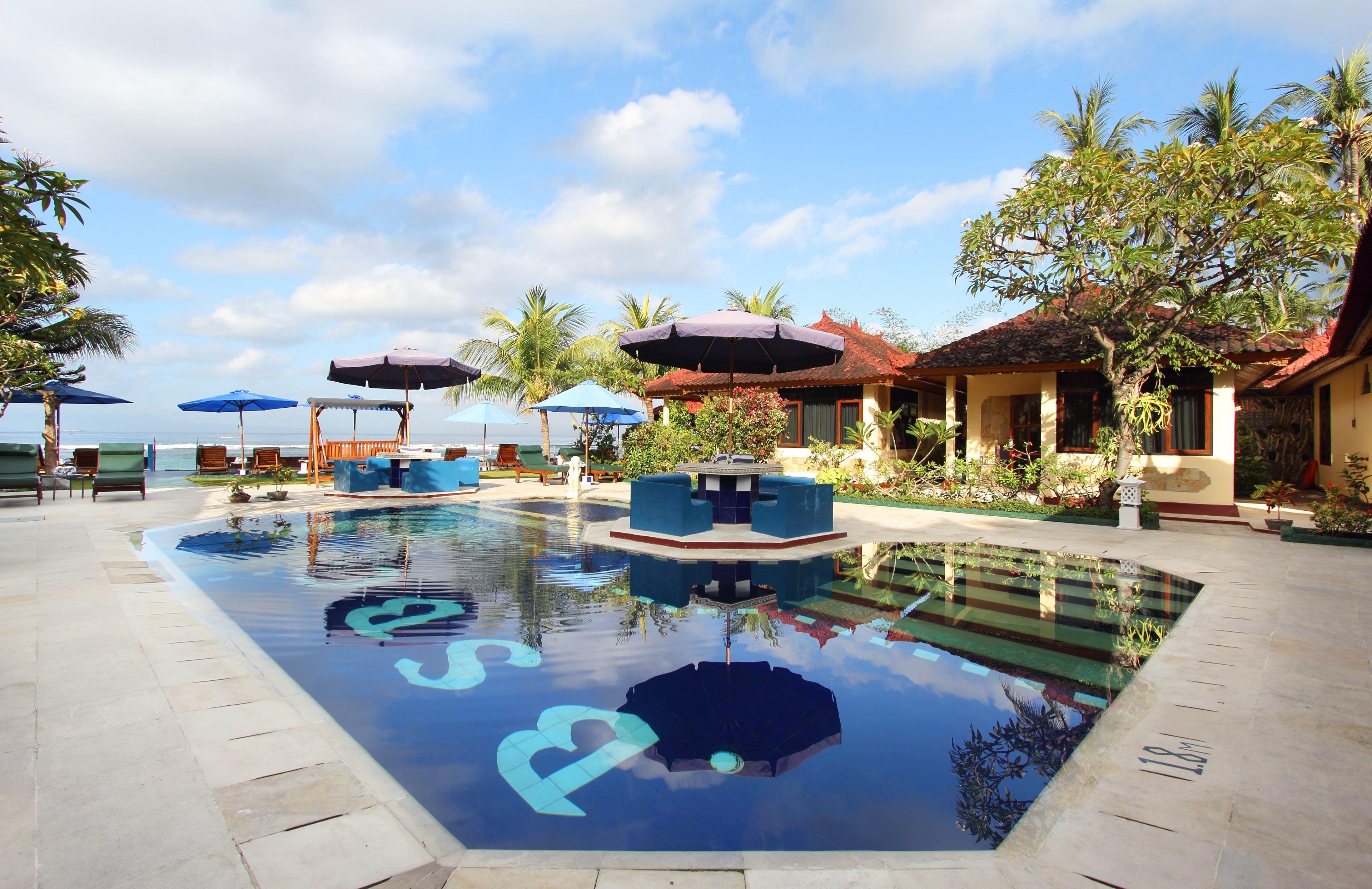 Un espace piscine aménagé avec des chaises longues, des parasols et une petite fontaine.