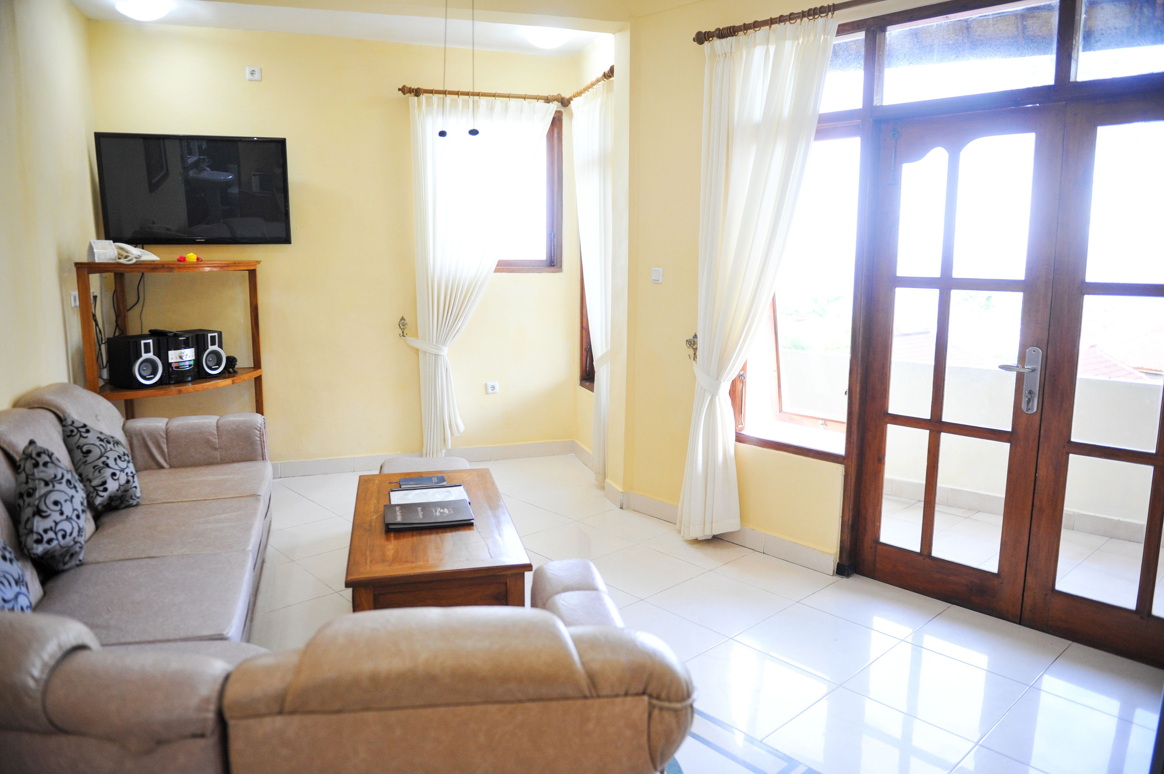 A living room with a sofa, a coffee table, a TV, and a window with curtains.