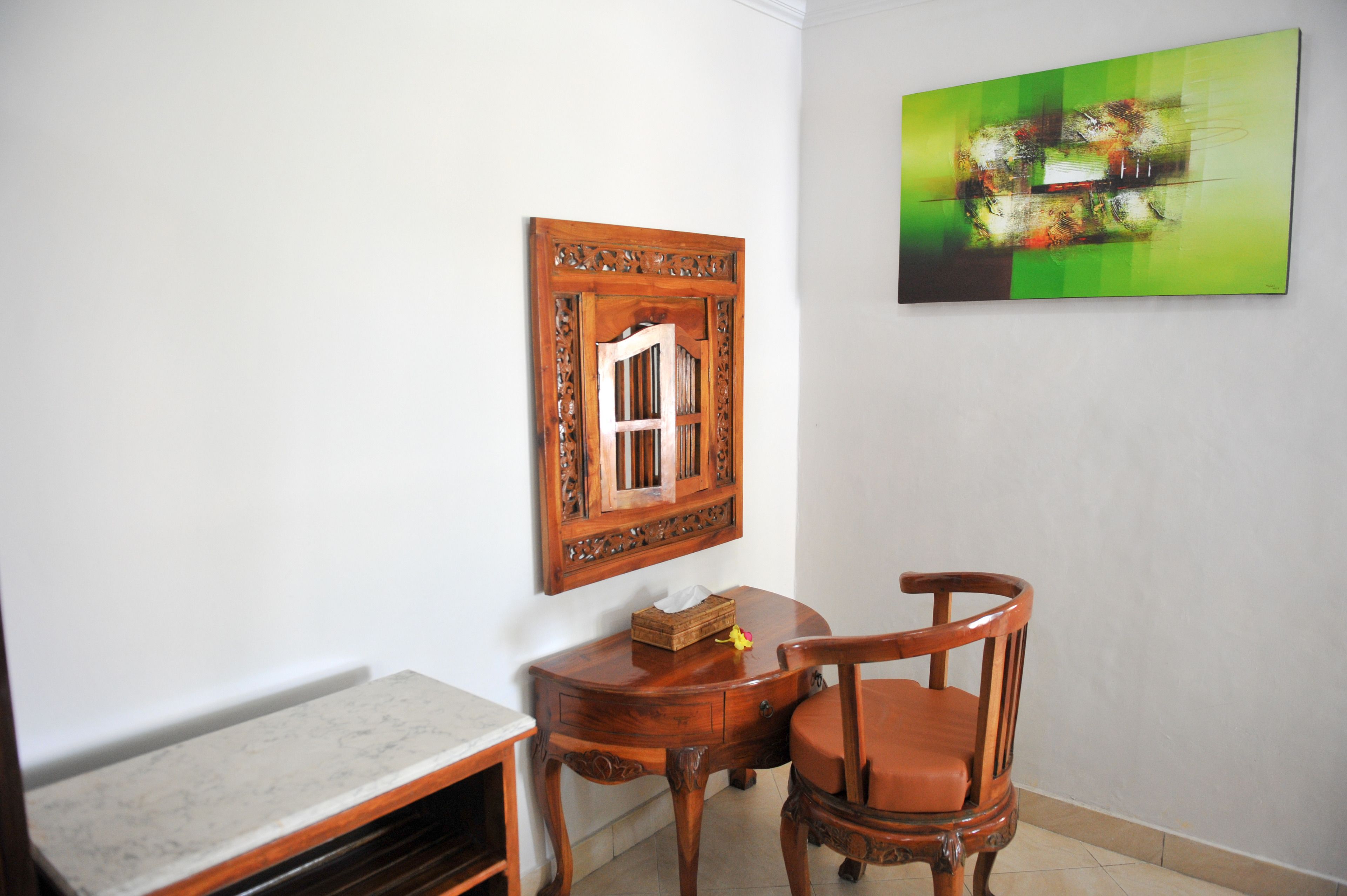 A room with a wooden chair, a small table, and a framed picture on the wall.