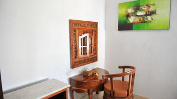 A room with a wooden chair, a small table, and a framed picture on the wall.