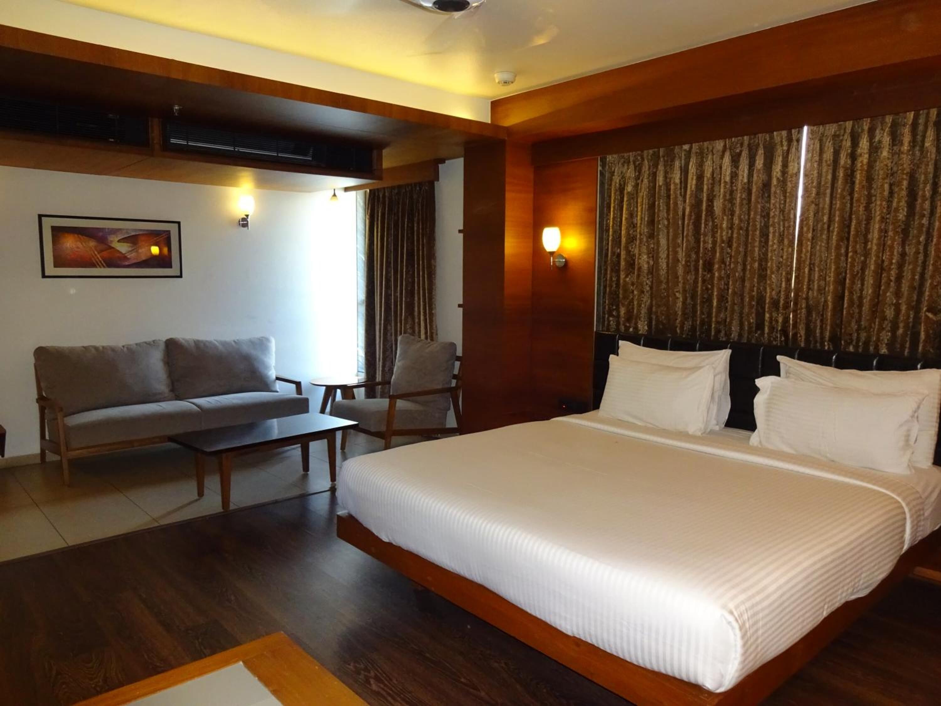 Una habitación de hotel con una cama grande, un sofá, una silla y una mesita.