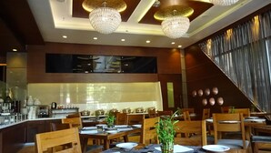 Un restaurant avec des tables et des chaises en bois, un coin bar et un lustre moderne.