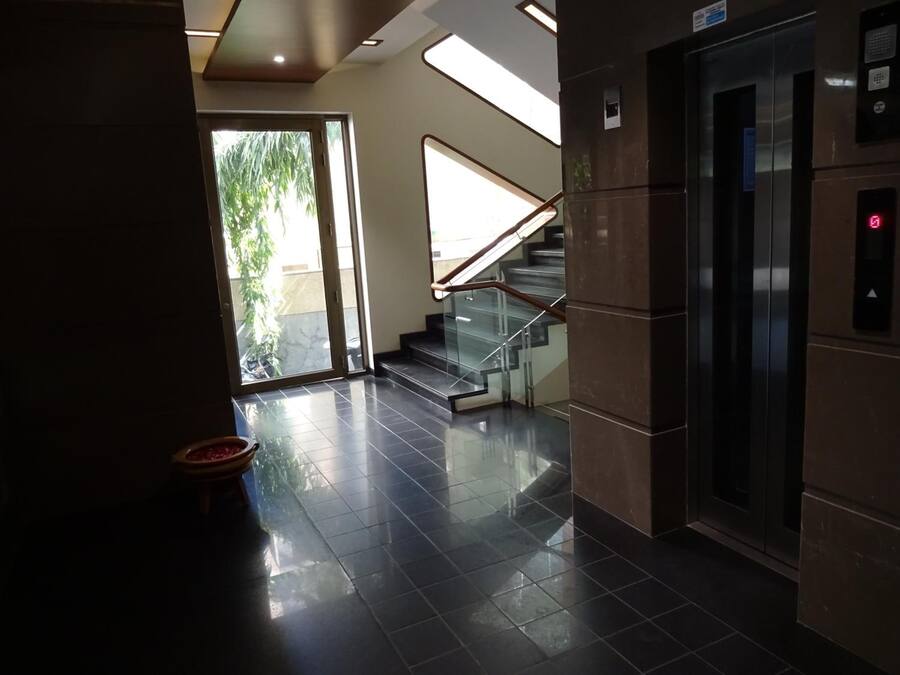 A modern interior with a glass staircase, a polished floor, and an elevator.