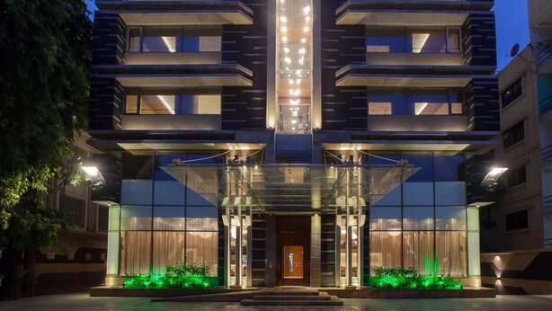 Un hôtel à plusieurs étages au design moderne, doté d’une entrée imposante avec des portes en verre et d’une bande lumineuse verticale.
