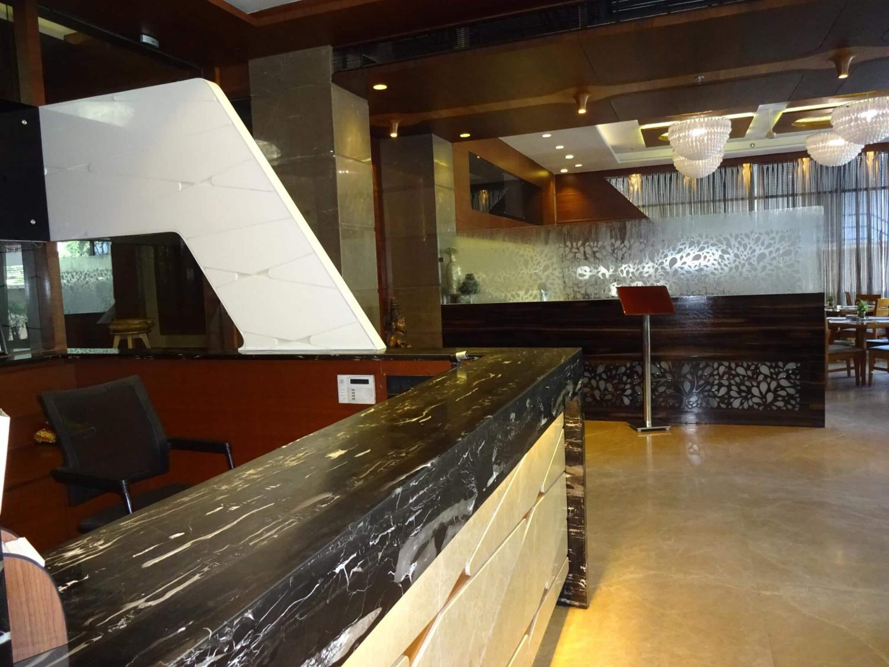 A reception area with a marble counter, a modern chandelier, and a decorative wall panel.