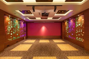 Un salón de conferencias con alfombra roja, paneles de madera y luces en el techo.
