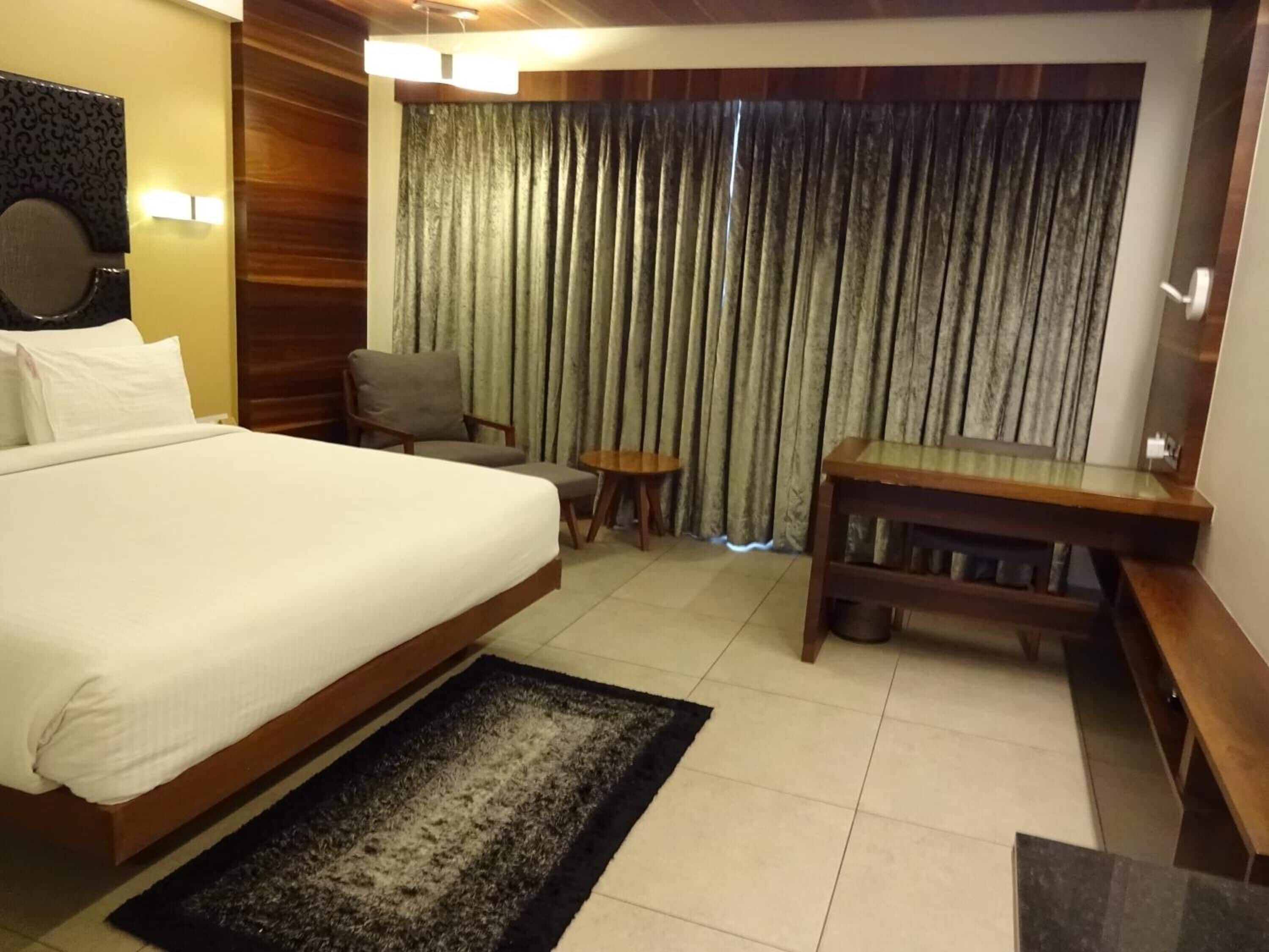 Ein Hotelzimmer mit einem großen Bett, einem Schreibtisch, einem Stuhl und einem kleinen Tisch.
