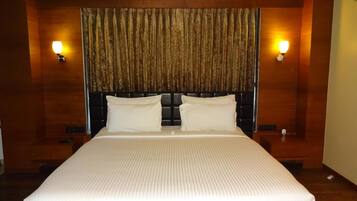 A large bed with a headboard, two bedside lamps, and a curtain.