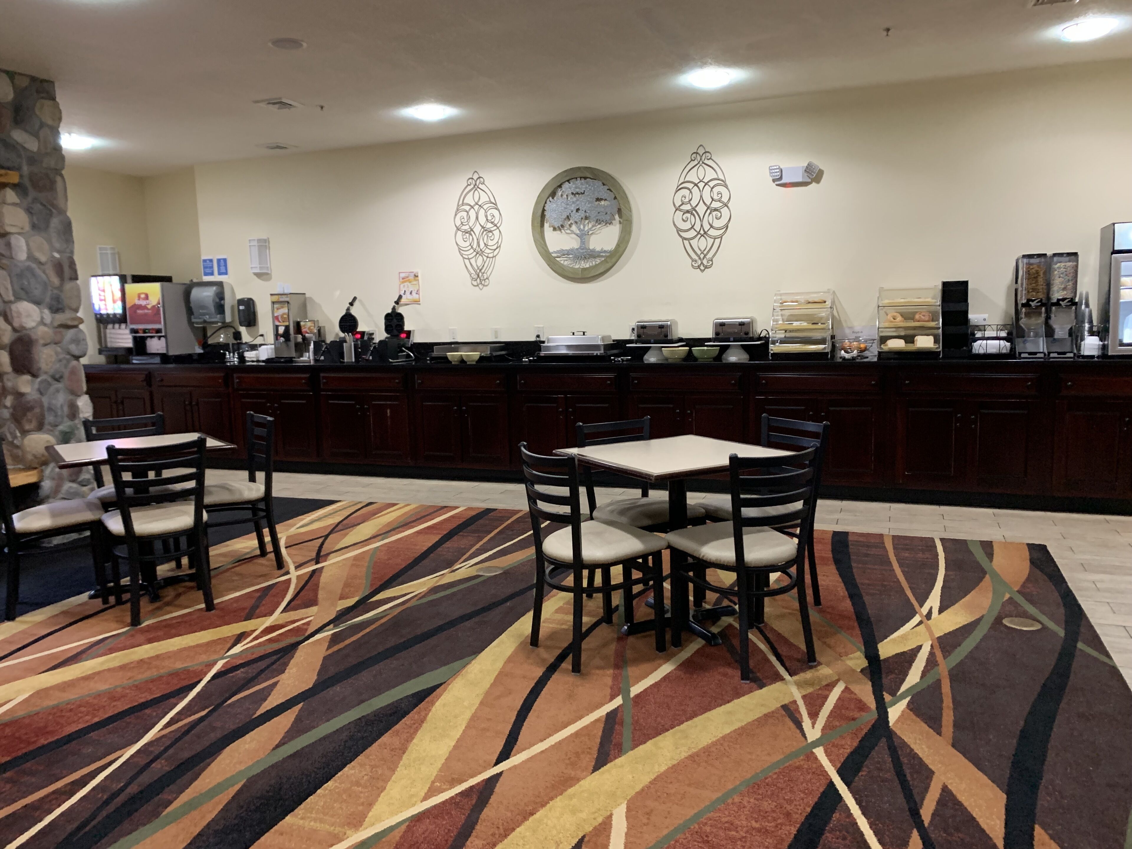 En hotellobby med en receptionsdisk, en vägg av sten och en mönstrad matta.