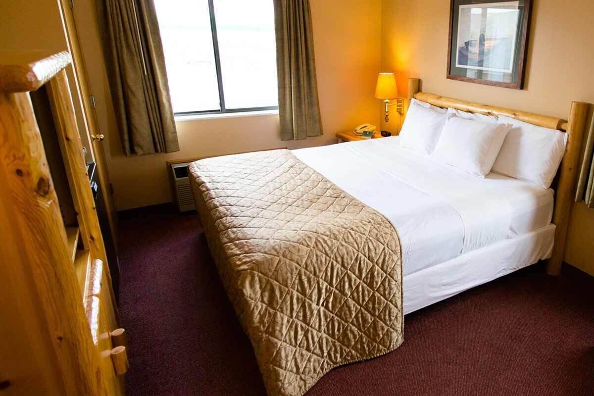 Een hotelkamer met een groot bed, een nachtkastje met een lamp en een stoel.