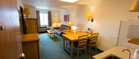 A compact hotel room with a kitchenette, a dining area, and a sofa.