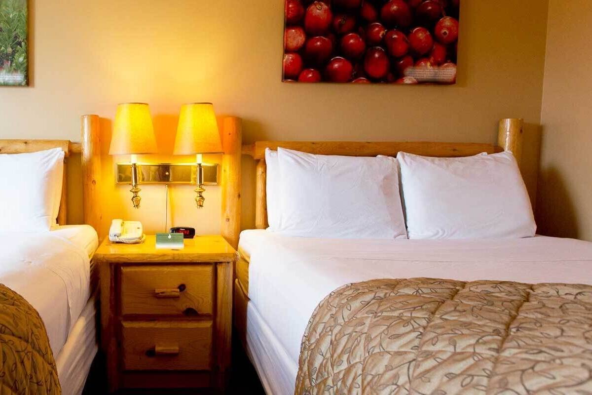 Een hotelkamer met twee enkele bedden, een houten nachtkastje met een lamp, een telefoon en een klein lade.