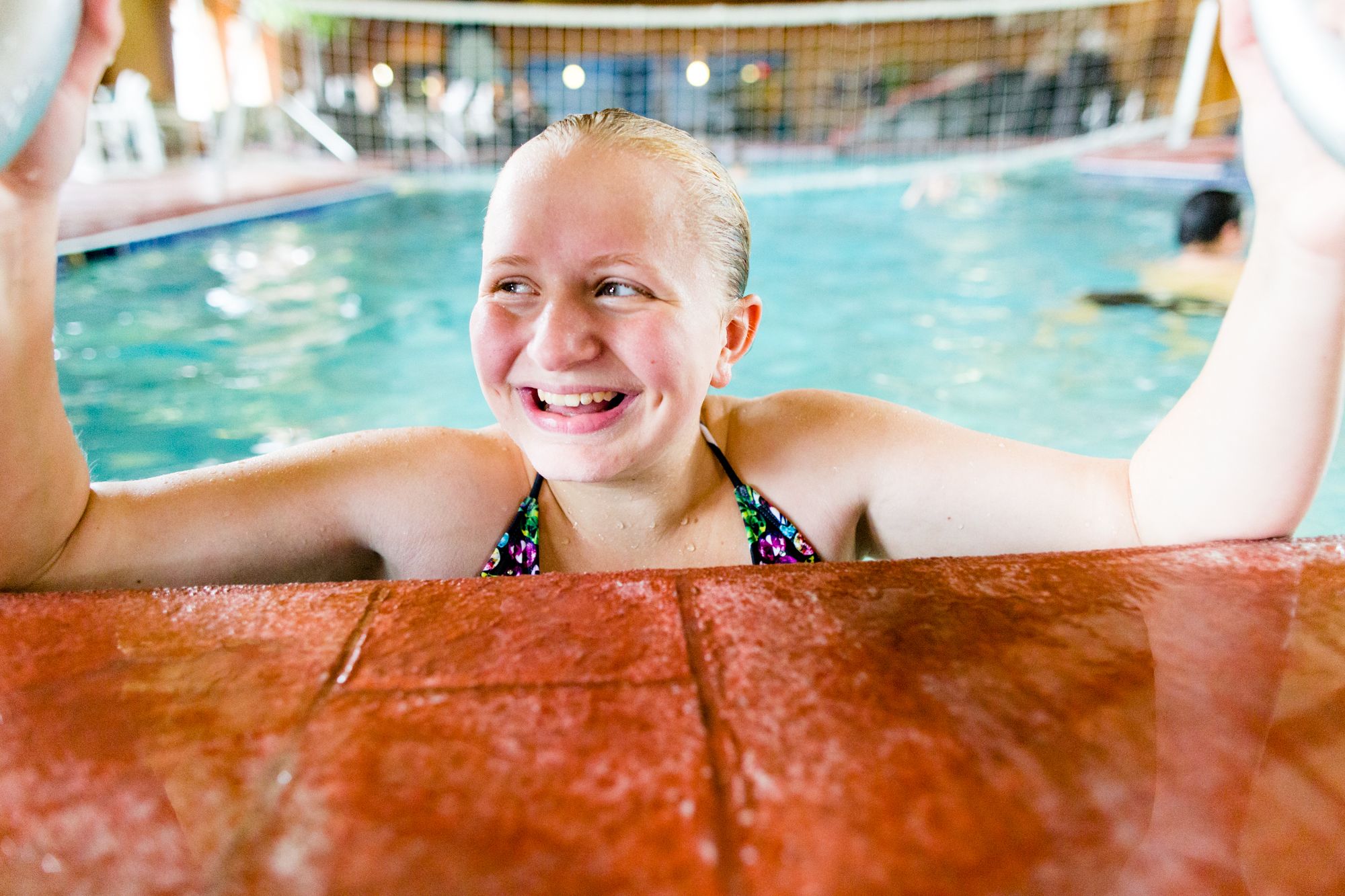 Une personne dans une piscine dont le bord est recouvert de carreaux.
