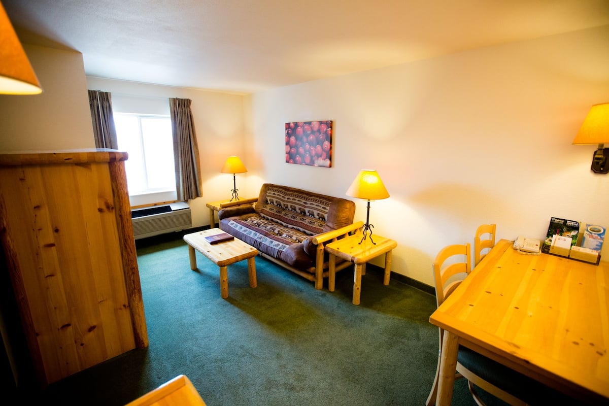 Een gezellige woonkamer met een bank, twee lampen, een klein tafeltje en een eettafel met stoelen.