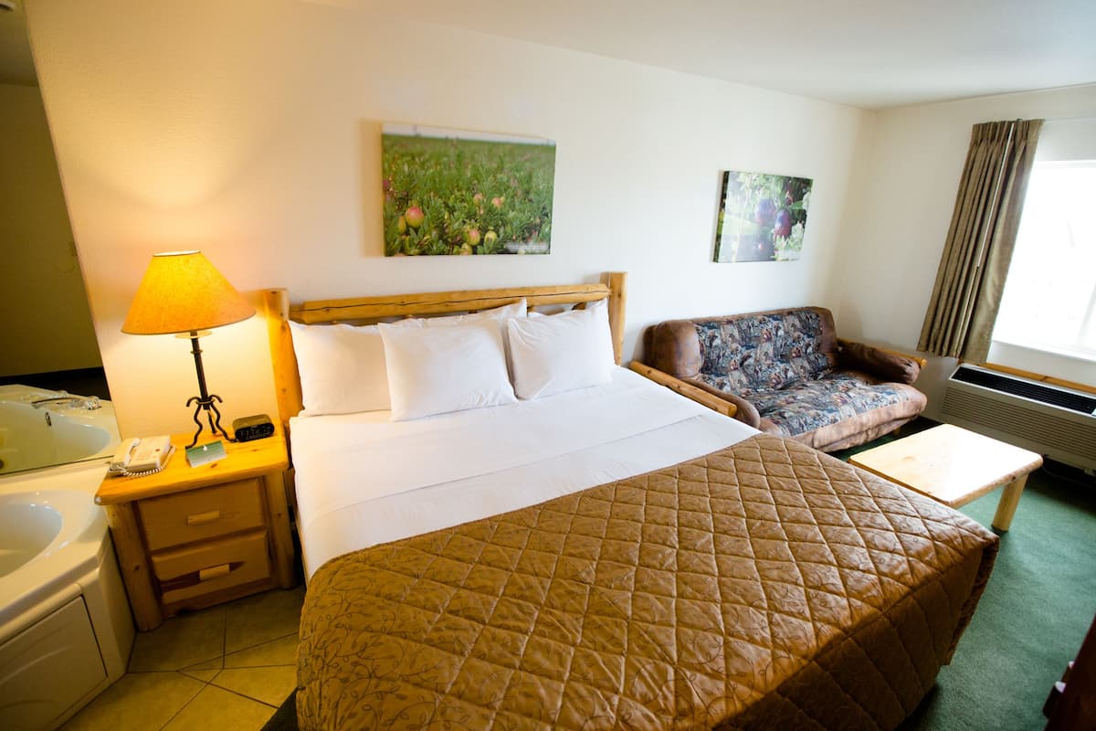 Een hotelkamer met een bed, een bank, een bureau, een lamp, een telefoon en een schilderij aan de muur.