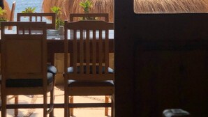 A beachside seating area with wooden chairs and a thatched roof structure. - Umbi Sharks Bay Diving Village (Sharm El Sheikh)