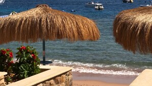 A beach with thatched umbrellas and a view of the sea. - Umbi Sharks Bay Diving Village (Sharm El Sheikh)