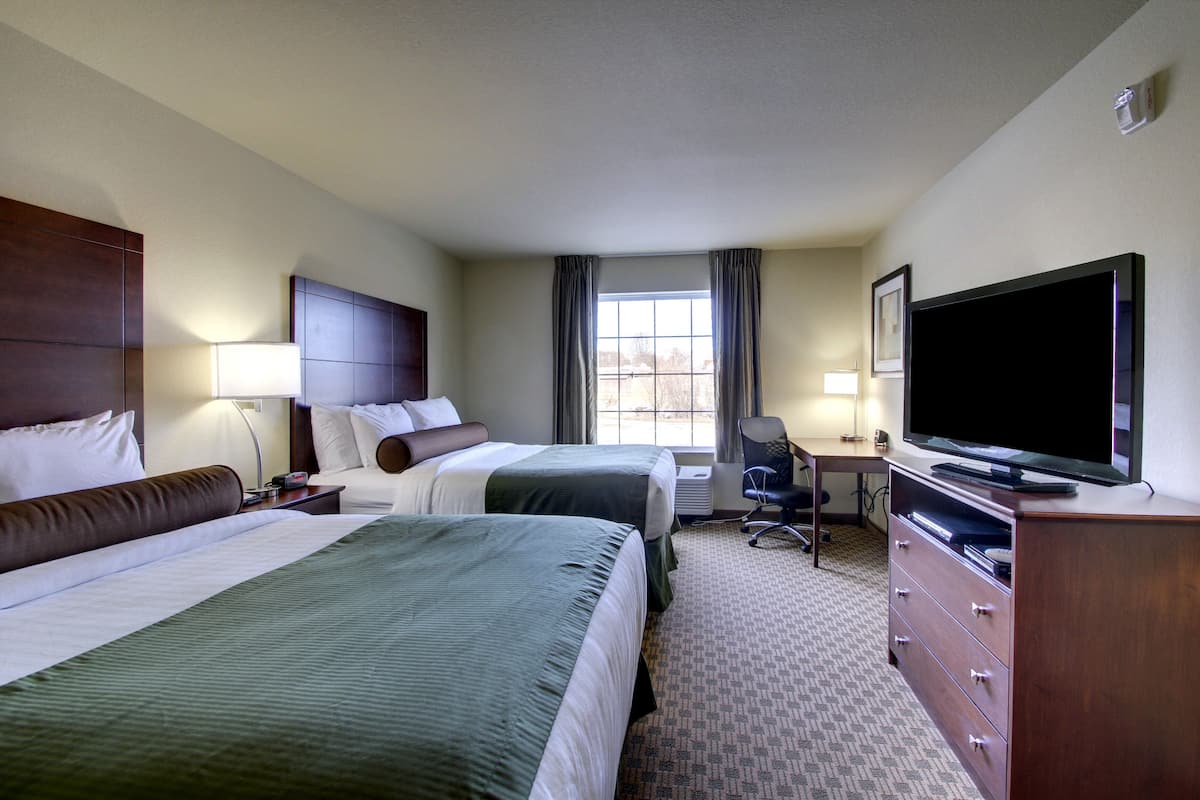 Une chambre d’hôtel avec deux lits, un bureau, une télévision et une commode.