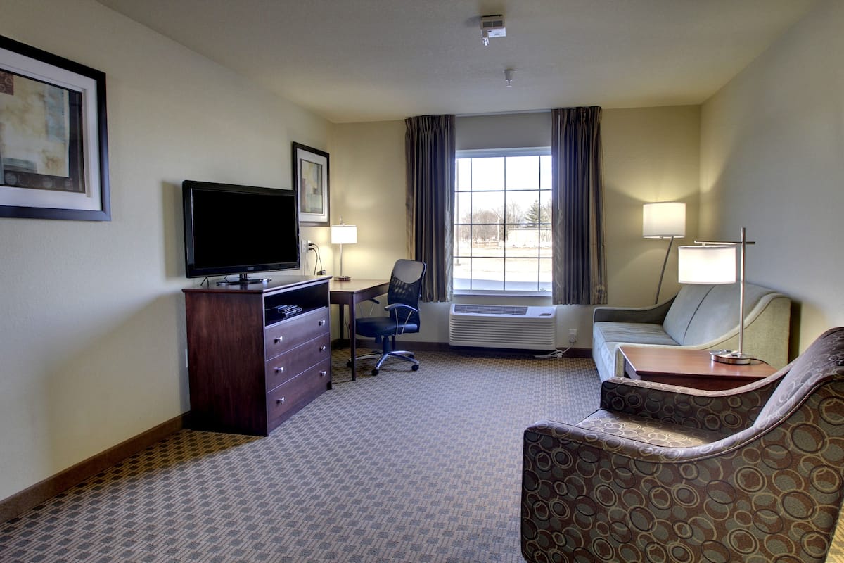 Une chambre d’hôtel équipée d’une télévision à écran plat, d’un bureau, d’une chaise, d’un canapé et d’une lampe.