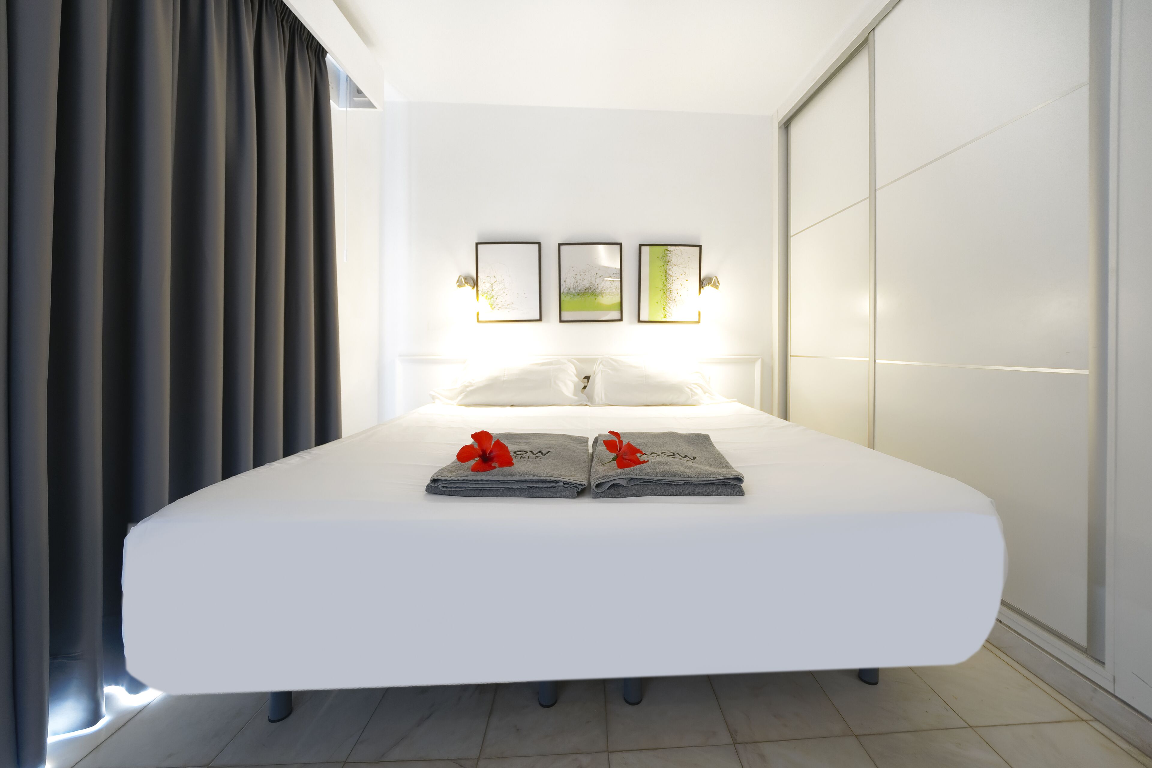 Ein modernes Hotelzimmer mit einem großen Bett, Blick auf die Stadt und einer Schiebetür.