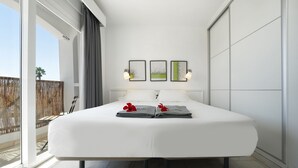Moderni hotellihuone, jossa on suuri sänky, parveke, jolta on näkymä, ja taideteoksia seinällä.