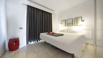 A modern hotel room with a large bed, a red stool, and a window with curtains.