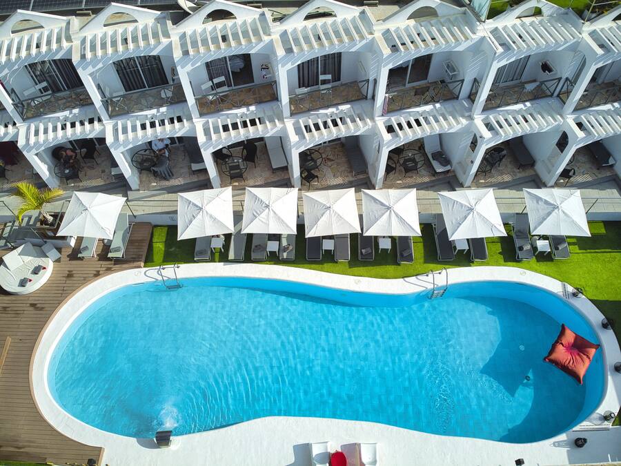 Una piscina con zona de terraza, sillas de descanso y sombrillas.
