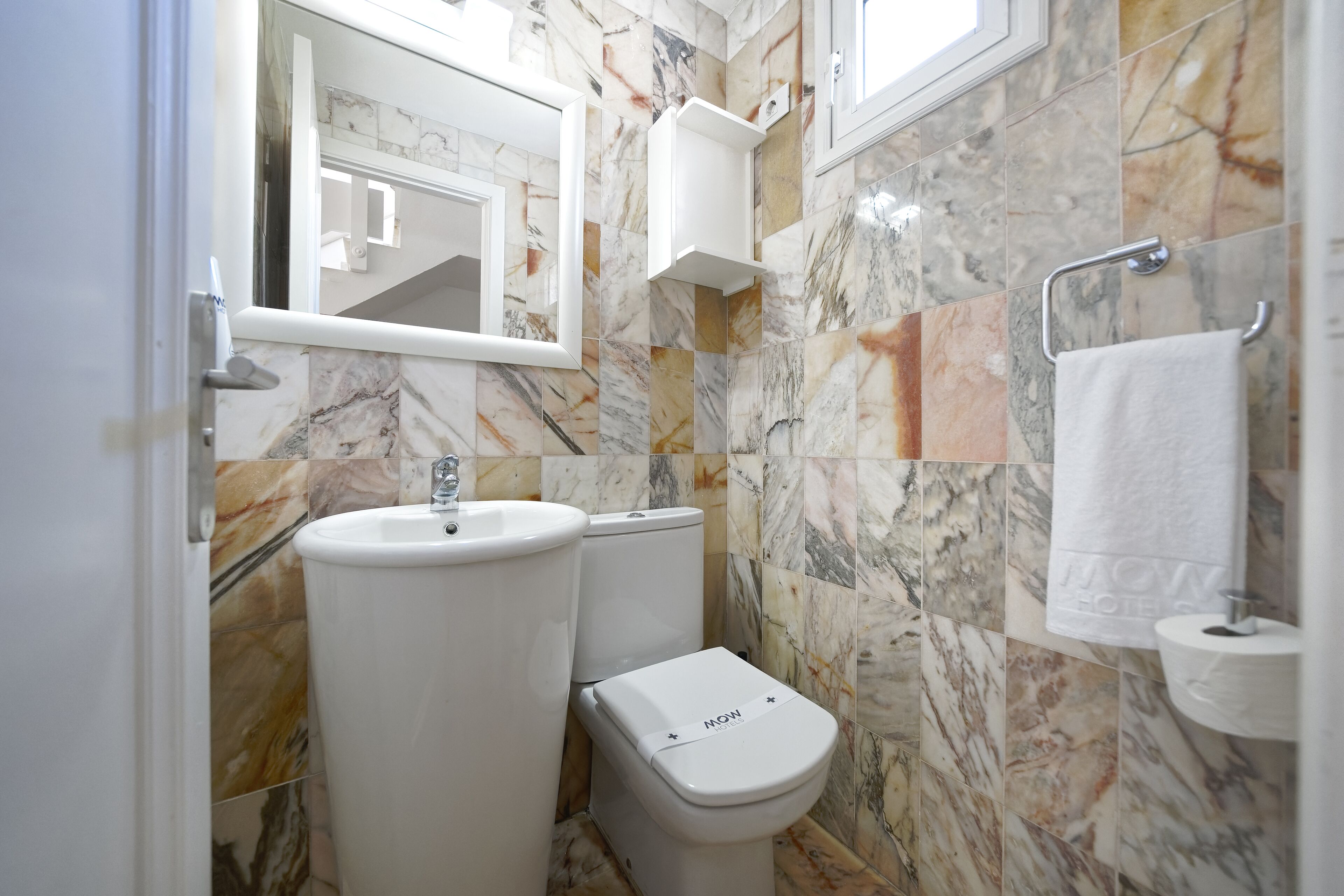 Un baño con lavamanos, inodoro y espejo.