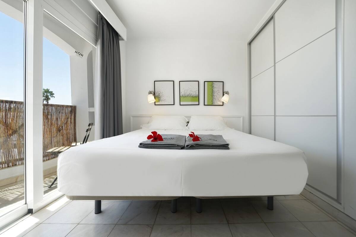 Une chambre d’hôtel avec un grand lit, un balcon offrant une belle vue et des œuvres d’art accrochées au mur.