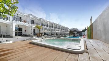 Zona de piscina con jacuzzi, sillas de descanso y una pileta.