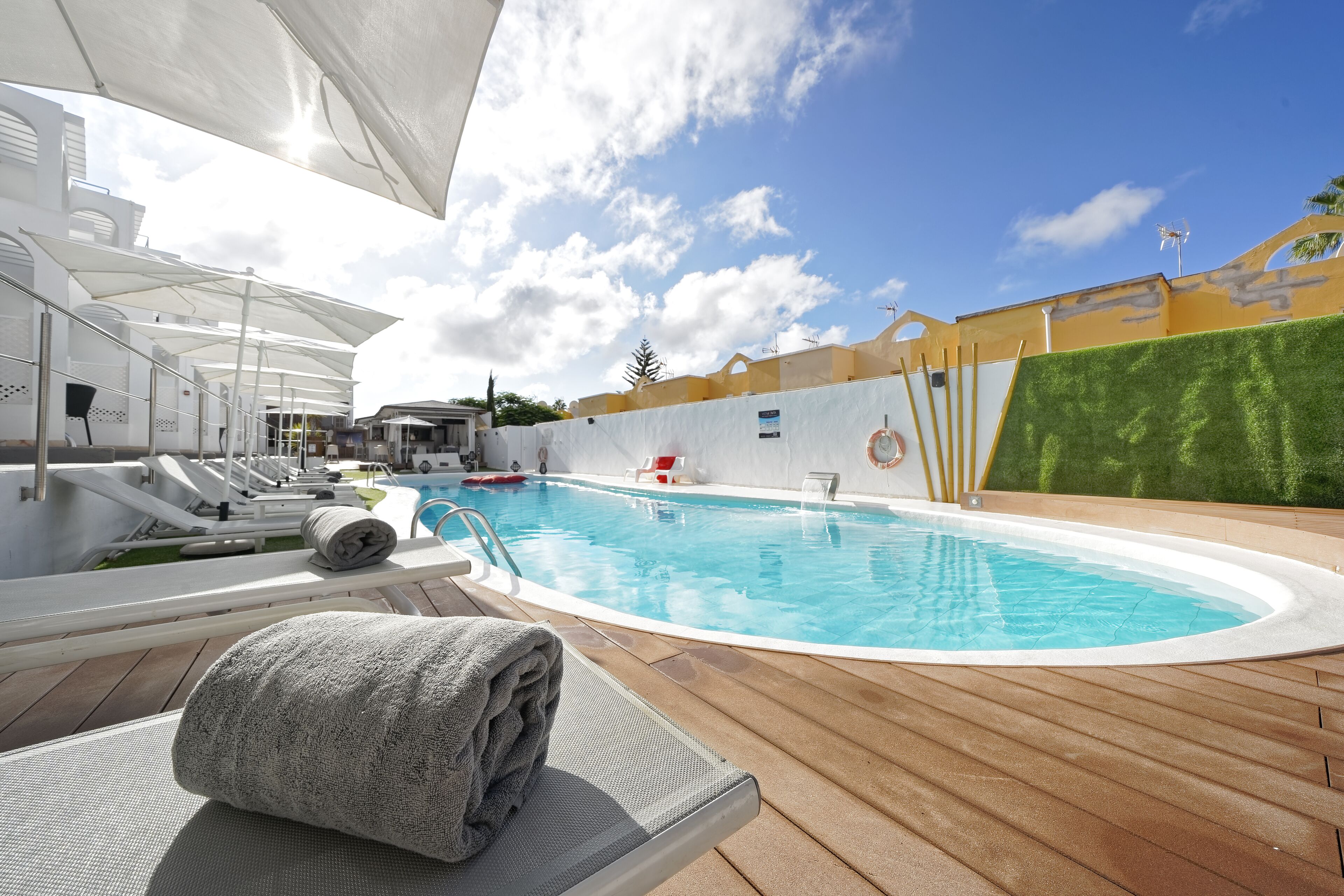 Una piscina al aire libre, sombrillas, sillones reclinables de piscina