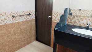 Un baño con un lavabo negro, un espejo, un perchero y una puerta.