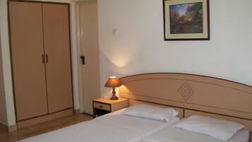 A hotel room with a bed, a nightstand with a lamp, a wardrobe, and a framed picture on the wall.