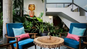 A modern indoor space with two blue armchairs, a round wooden table, and a staircase. -  Sonitori Boutique Resort (Phnom Penh)