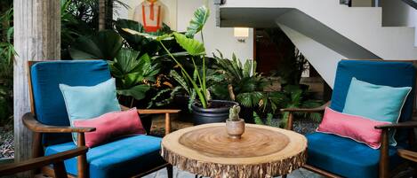 A modern indoor space with two blue armchairs, a round wooden table, and a staircase.