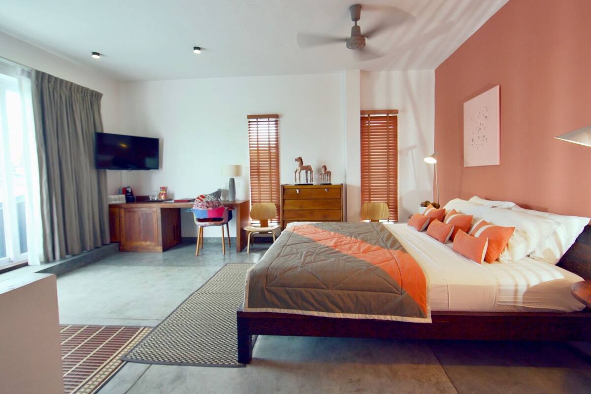 A bedroom with a bed, desk, chair, and a television.