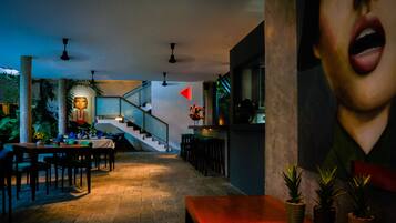 A restaurant with a staircase, wooden tables, and potted plants.