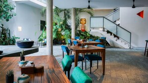 A spacious indoor area with a wooden dining table, blue chairs, and various plants. -  Sonitori Boutique Resort (Phnom Penh)