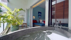 A modern bathroom with a large bathtub, a potted plant, and a view of a bedroom with a bed and a painting. -  Sonitori Boutique Resort (Phnom Penh)