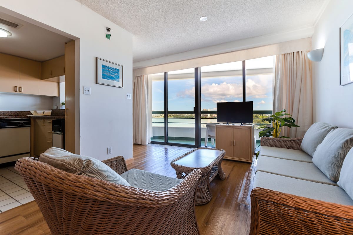 A modern living area with wicker furniture, a sofa, a small table, and a television.
