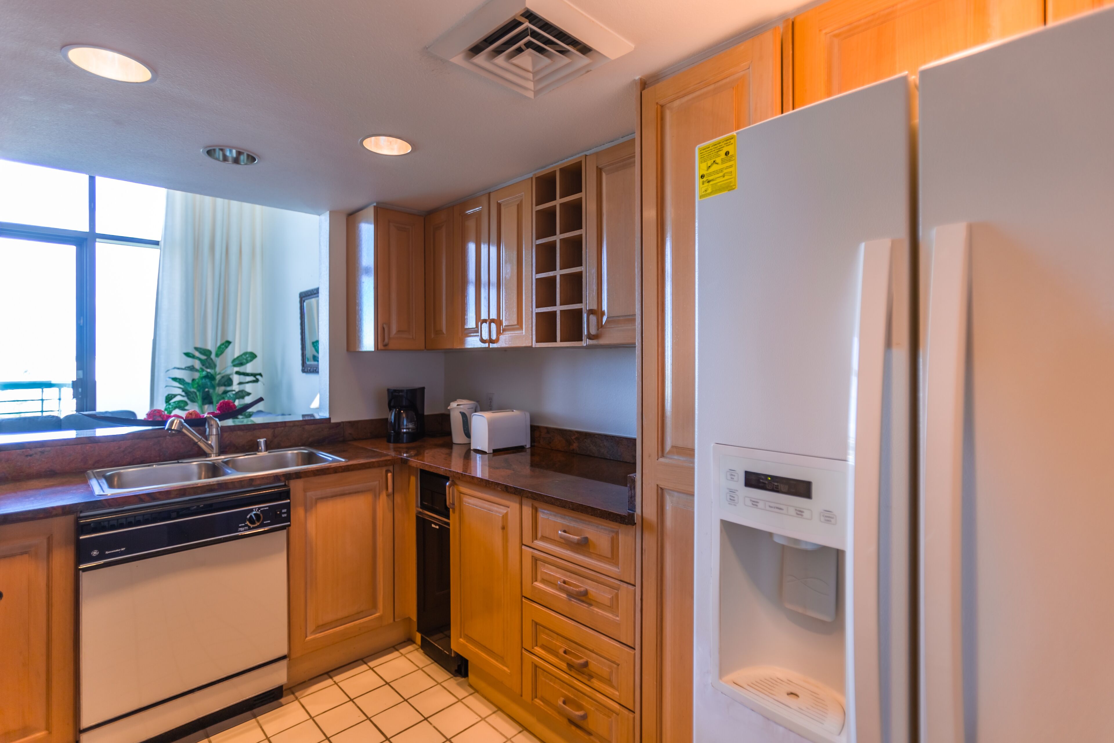 A modern kitchen with wooden cabinets, a dishwasher, a refrigerator, and a coffee maker.