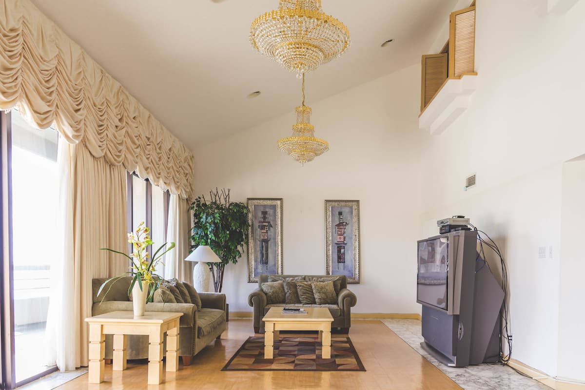 A living room with a chandelier, sofa, coffee table, television, and artwork on the wall.