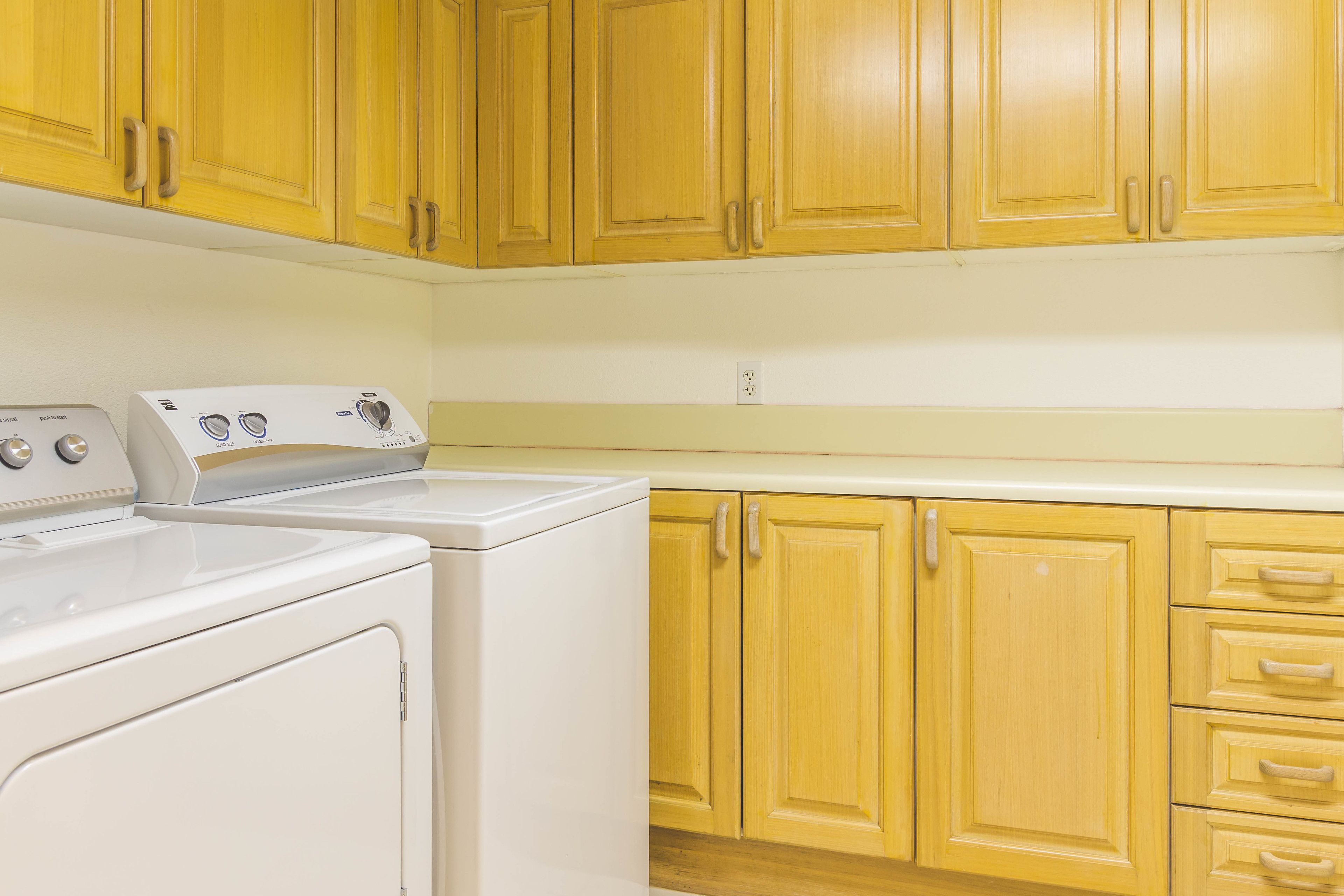 A kitchen with wooden cabinets and a white washing machine.