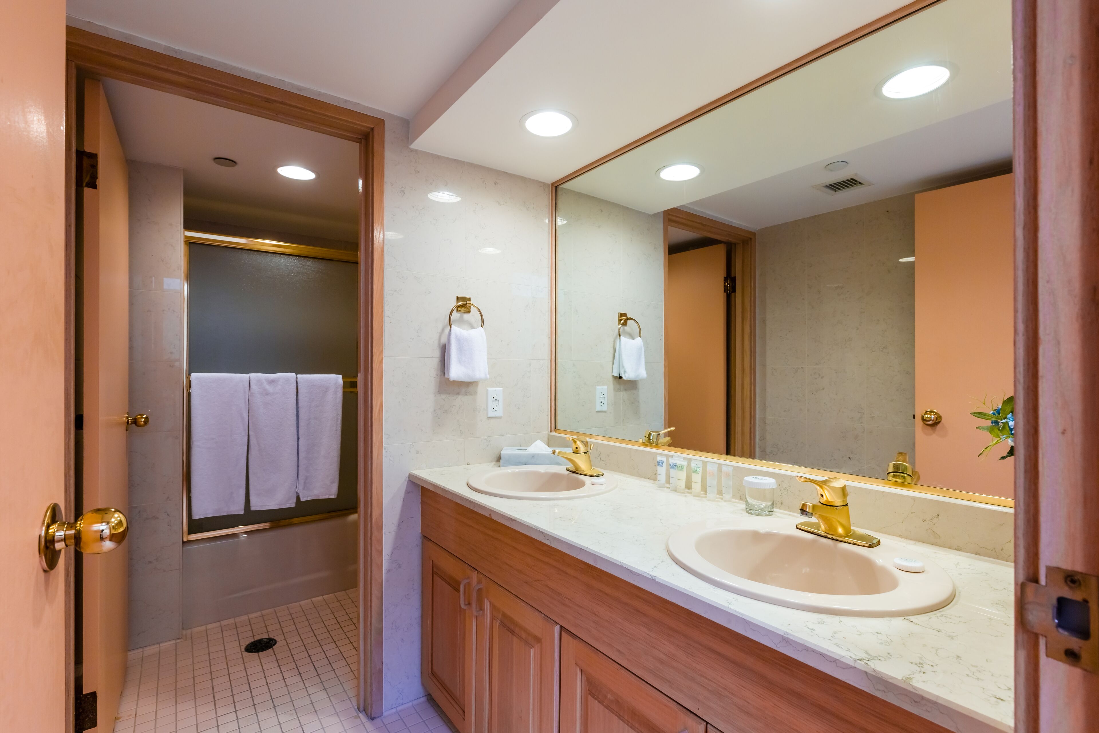 A modern bathroom with two sinks, a large mirror, and wooden cabinetry.