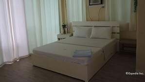 A bedroom with a bed, curtains, a bedside table with a vase, and a wall-mounted air conditioning unit. - Moalboal Beach Resort (Moalboal)